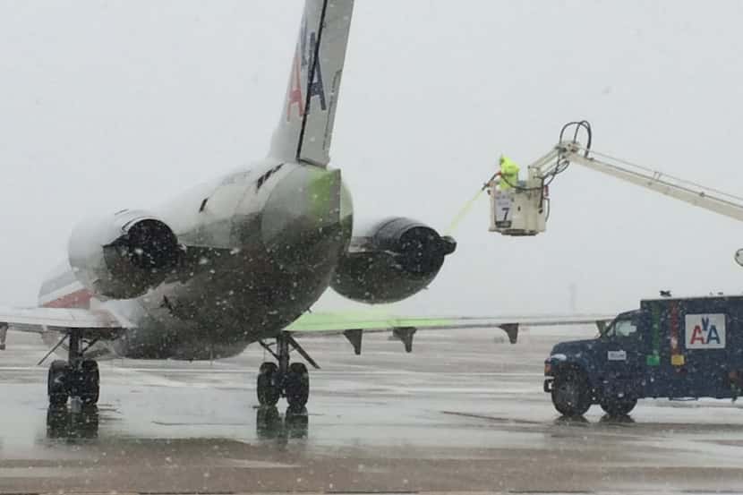 American Airlines crew members work to de-ice planes at DFW airport on Friday, Feb. 27,...