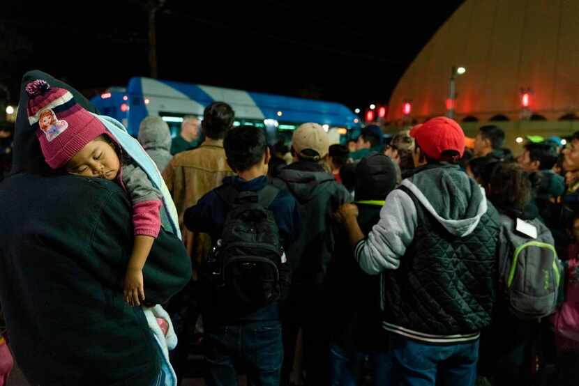 Asylum seekers stand at a bus stop after they were dropped off by Immigration and Customs...