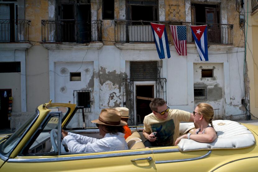 FILE - In this March 20, 2016 file photo, tourists ride in a classic American car past a...
