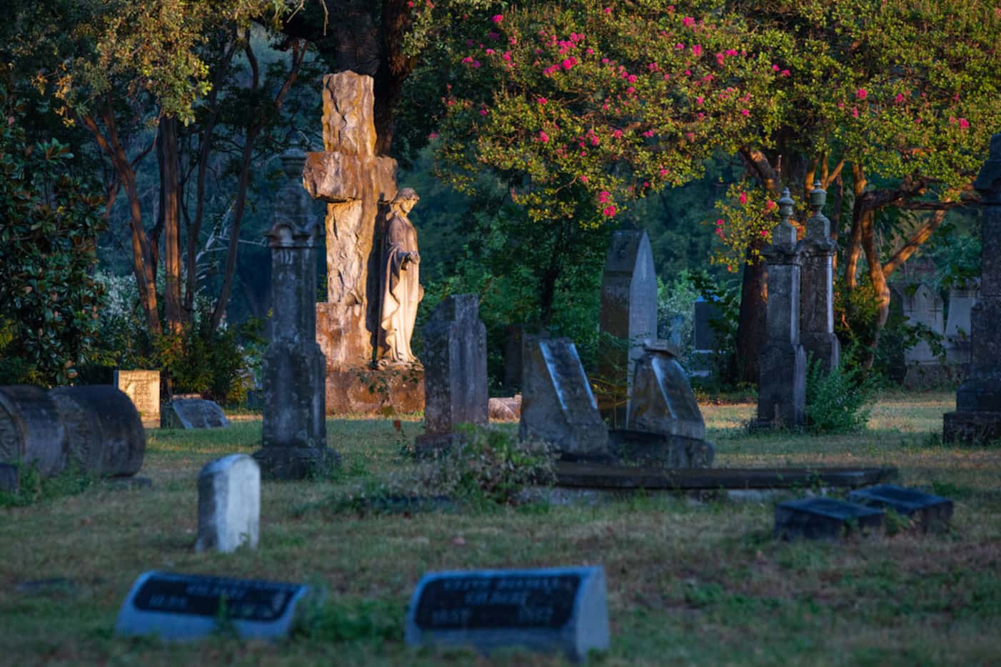 The rising sun shines on a headstone at the Oakland Cemetery in South Dallas on Thursday.