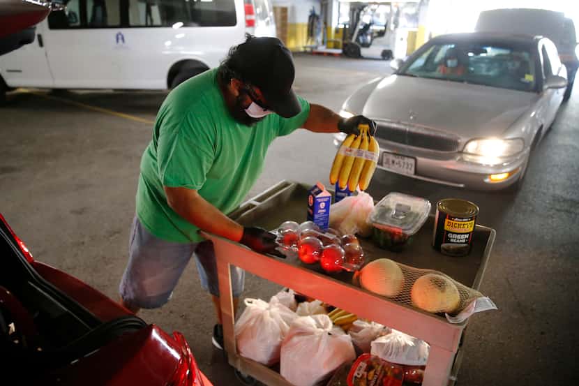 Oscar Espinosa works on putting food in a vehicle during a drive-through food distribution...