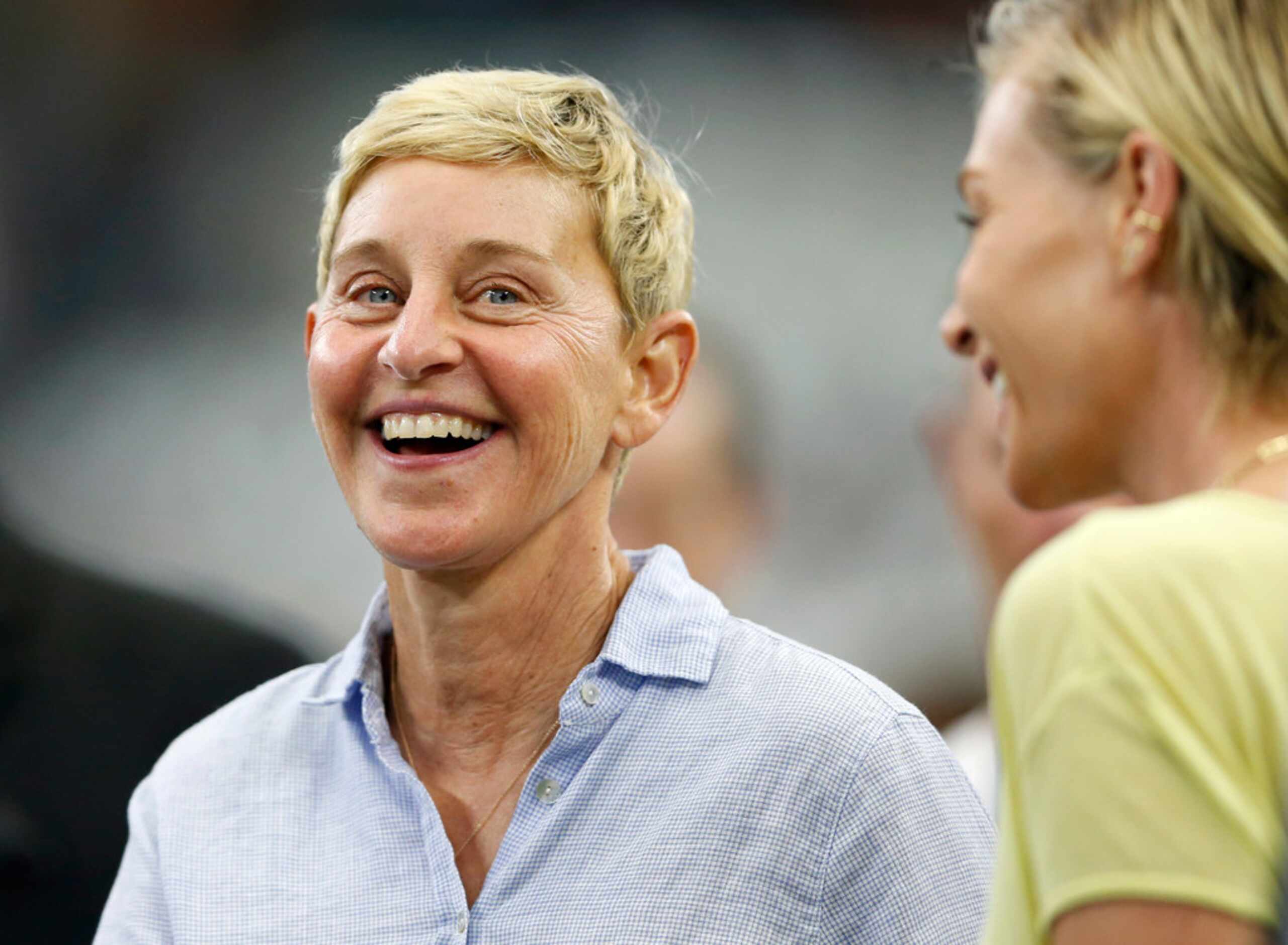 Ellen DeGeneres smiles as she watches warmups on the sideline before a game between the...