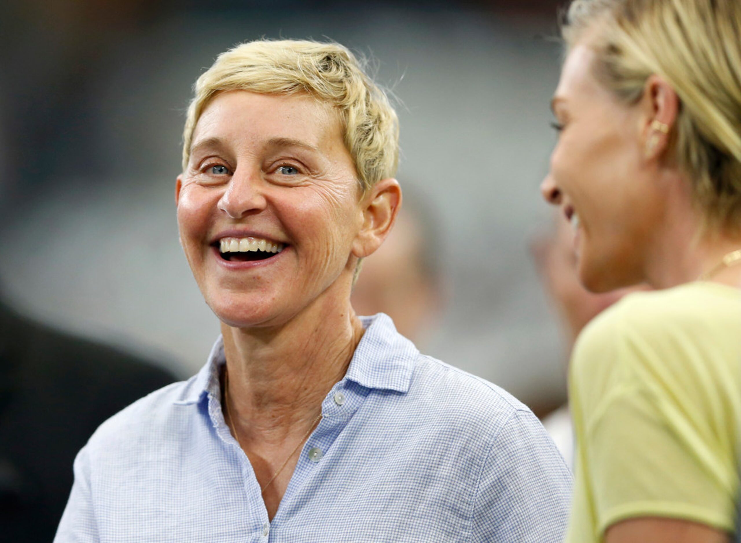 Ellen DeGeneres smiles as she watches warmups on the sideline before a game between the...