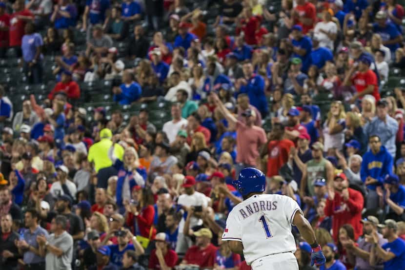 Texas Rangers fans cheer as shortstop Elvis Andrus runs to first as he drives in a run with...
