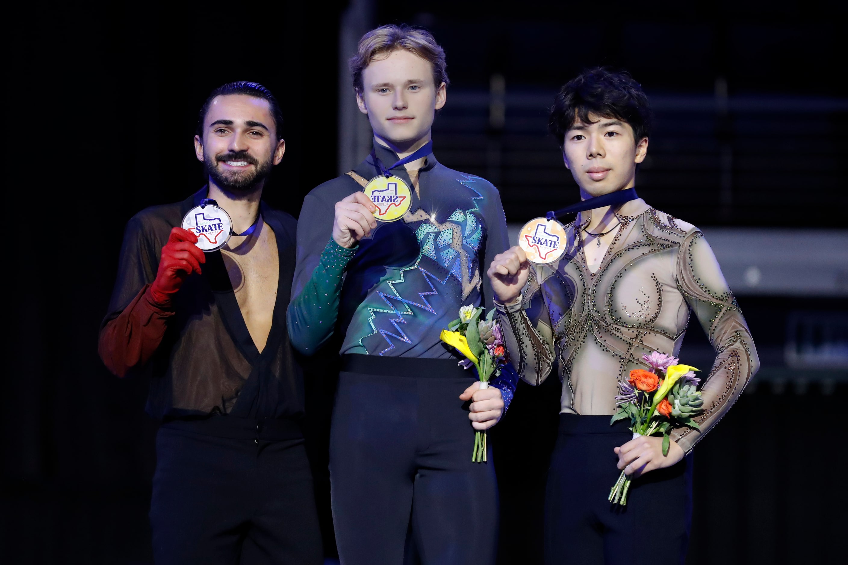 Ilia Malinin, of the United States, center, poses for photos after winning the gold medal in...