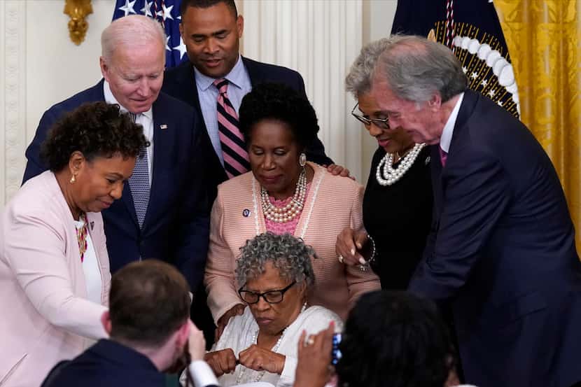People take photos as Opal Lee holds a pen and is seated where President Joe Biden signed...