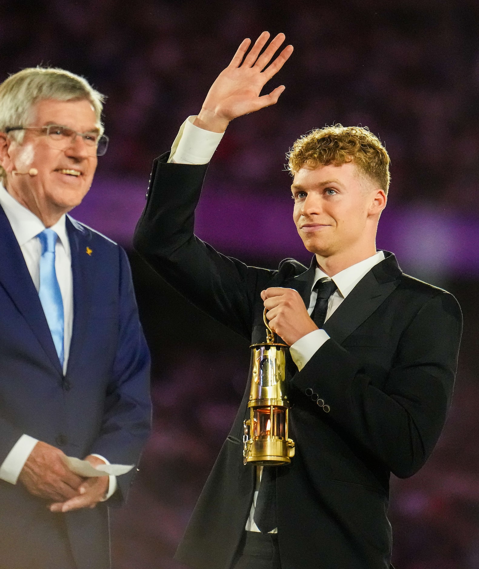 French swimmer Leon Marchand carries a lantern containing the Olympic flame to IOC President...