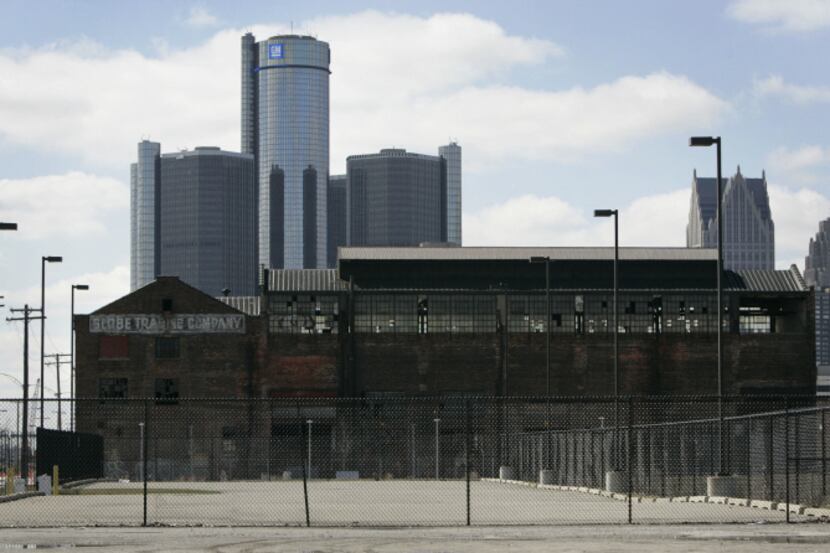 The Renaissance Center, where General Motors has its headquarters, towers over abandoned...
