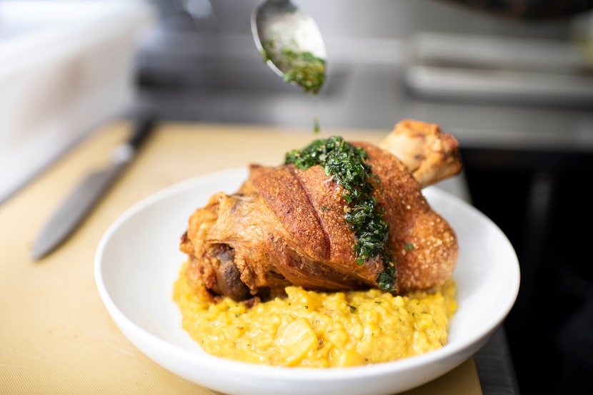 Chef Marshall Cole drizzles salsa verde over a Crispy Pork Shank at The Mitchell in downtown...