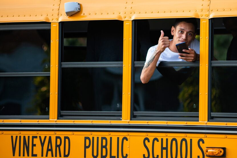 A man, who is part of a group of immigrants that had just arrived, flashes a thumbs up...