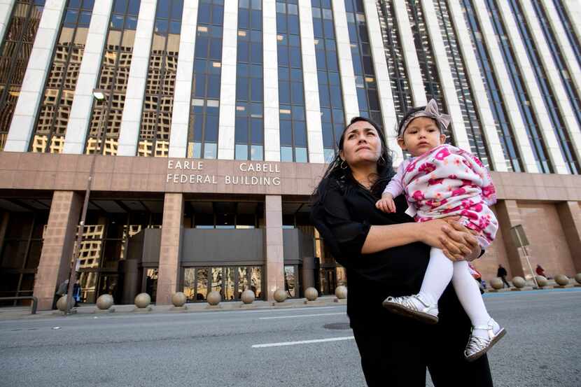 Lucia Mejia holds her 19-month-old daughter Teresa outside the Earle Cabell Federal Building...