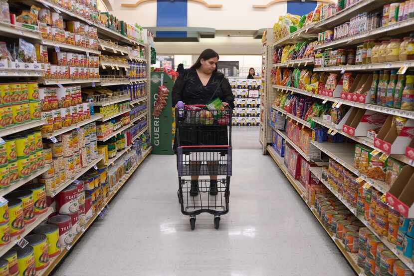 Jaqueline Benitez pushes her cart down an aisle as she shops for groceries at a supermarket...