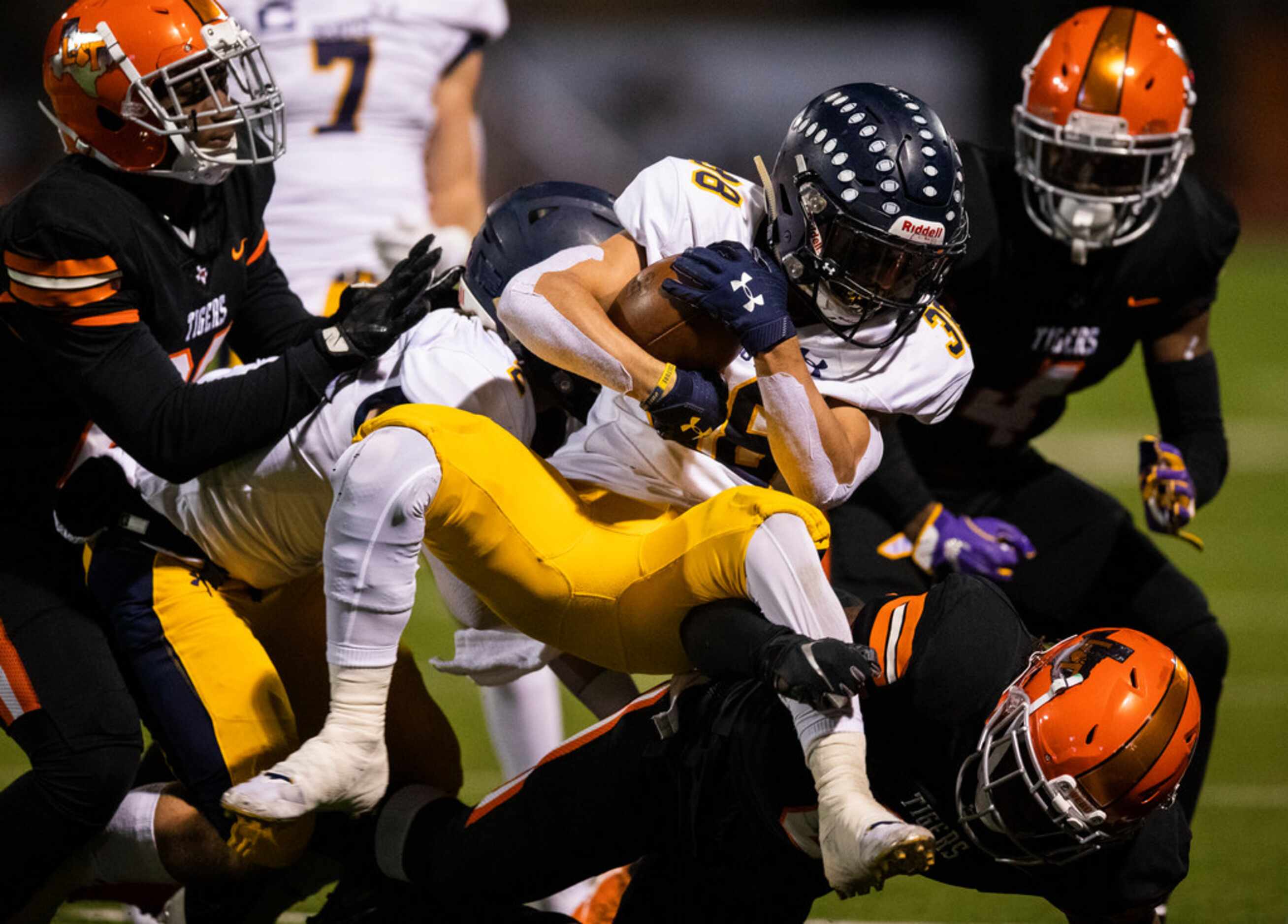 Highland Park running back Heath Hunter (38) is tackled by Lancaster defensemen during the...