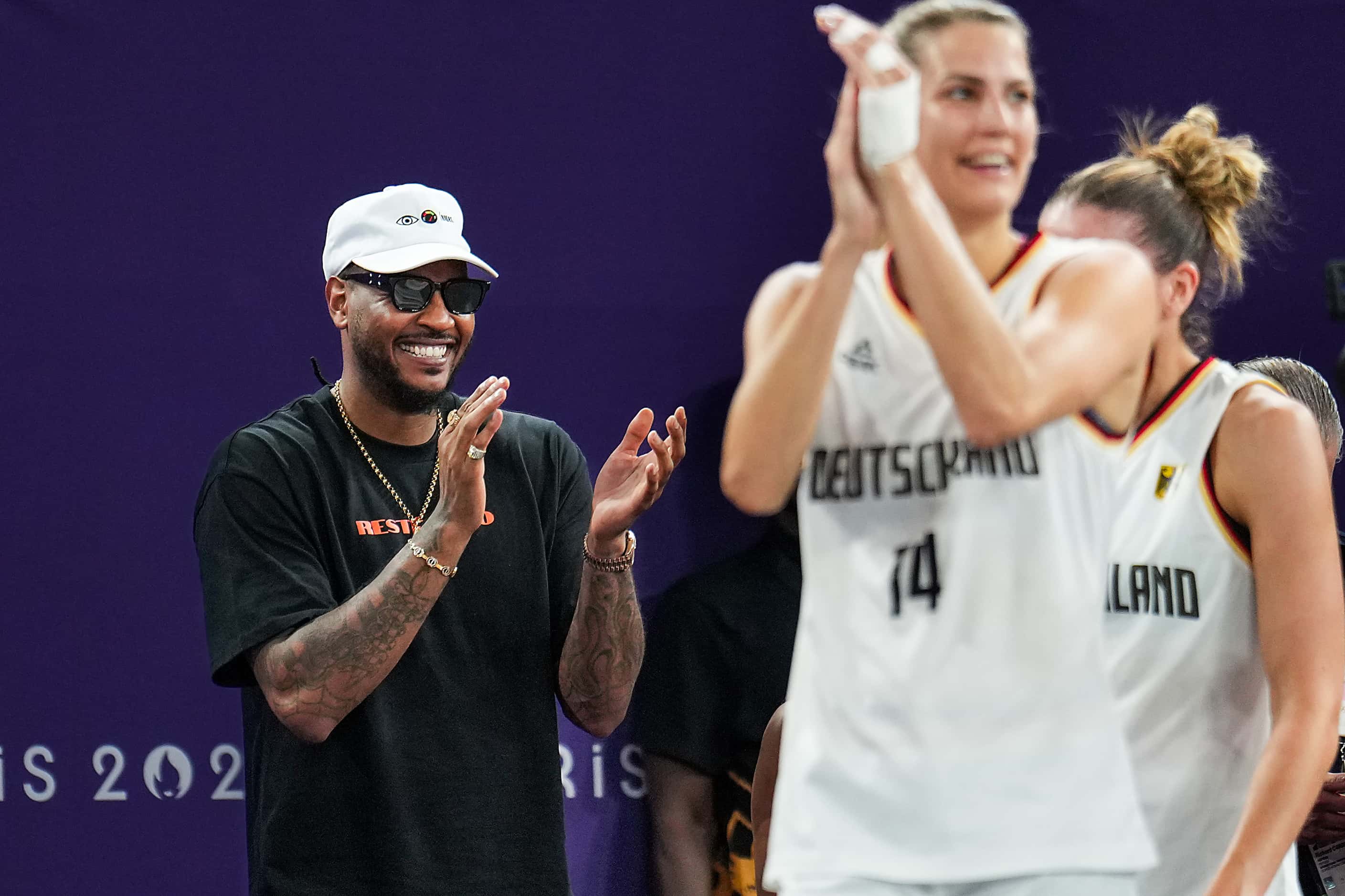 Former NBA player Carmelo Anthony applauds as Germany celebrates a victory over Spain for...