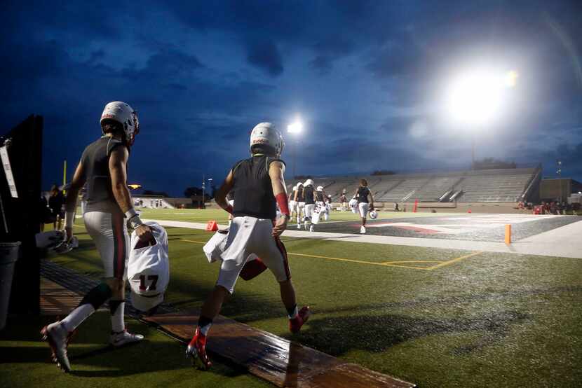 Coppell player walk onto the field at Pennington Field after a lightning delay prior to...