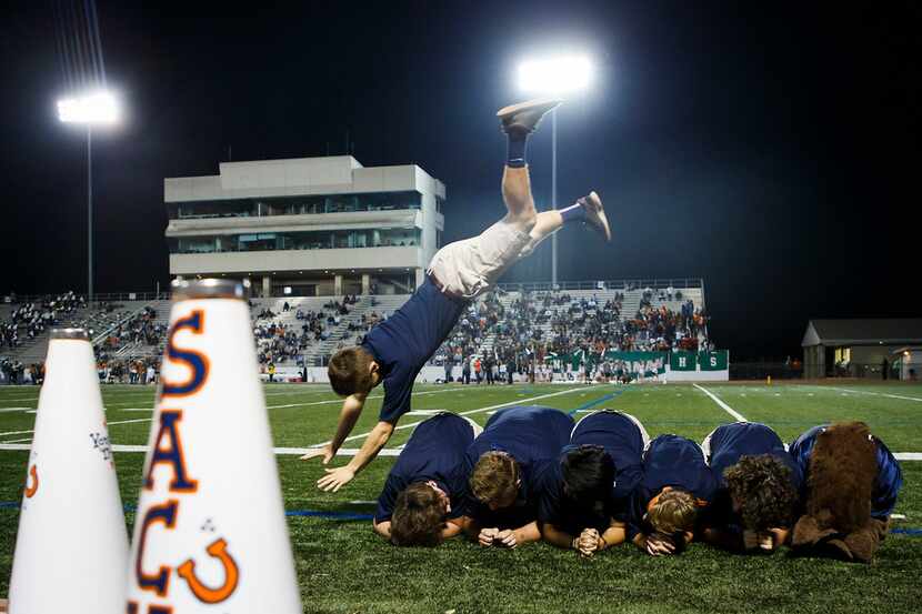 Payton Fozkos, a member of the Sachse Wranglers, vaults over his teammates on the sidlelines...