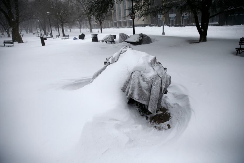  Belongings where homeless people are known to sleep are covered in snow on a bench in a...