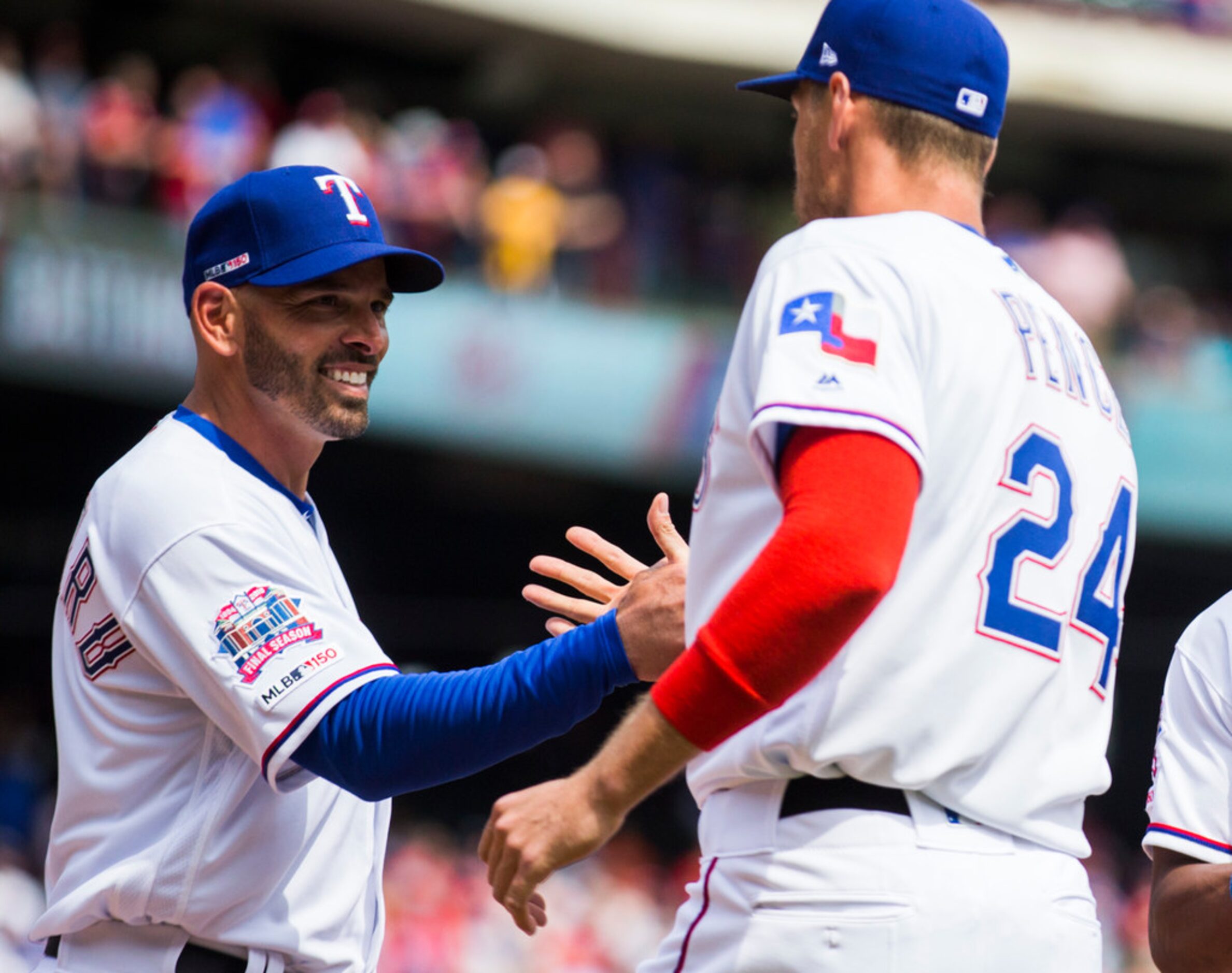 Texas Rangers manager Chris Woodward (8) greets designated hitter Hunter Pence (24) before...