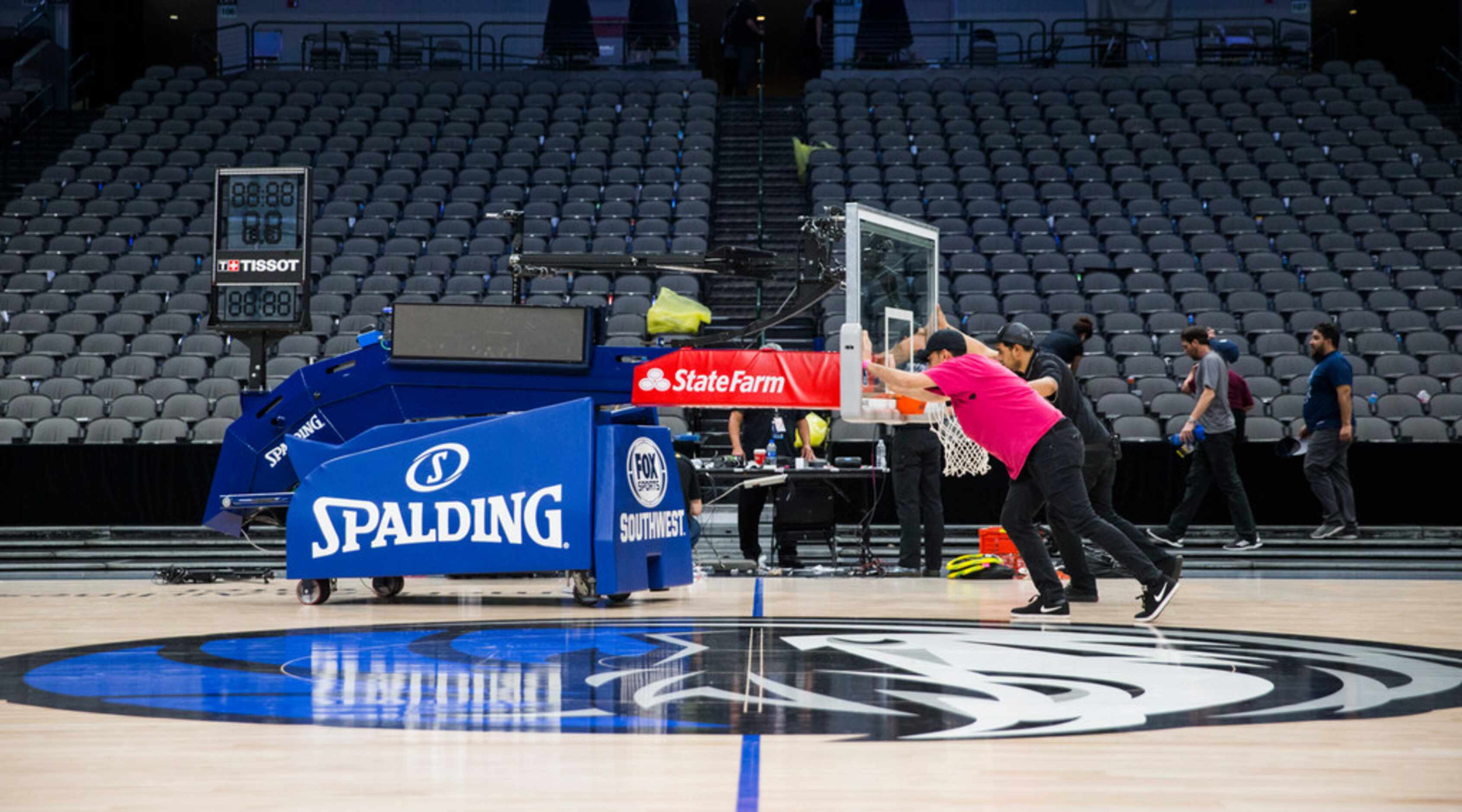 Crews remove a basketball hoop from the court after the Dallas Mavericks beat the Denver...