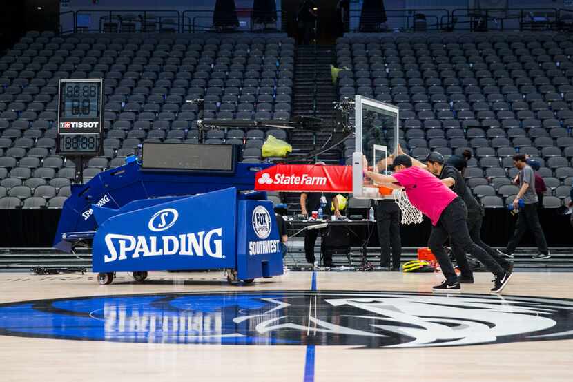 FILE - Crews remove a basketball hoop from the court after the Mavericks beat the Denver...