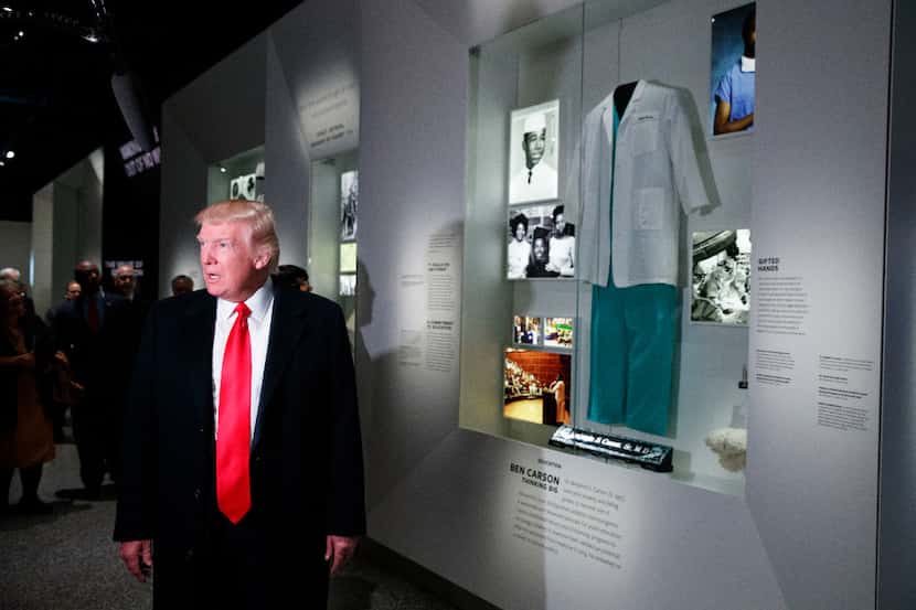 President Donald Trump talks with reporters as he stops at the exhibit for Dr. Ben Carson,...