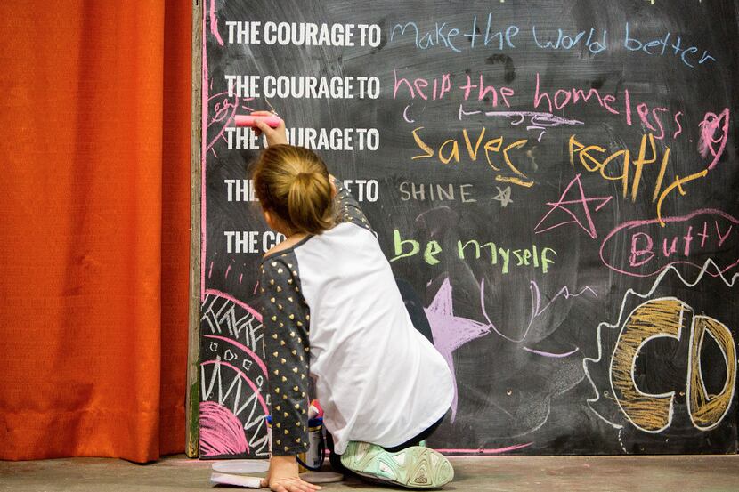 A Day 1 Dallas attendee draws on the Courage Wall. The festival, which was held at Fair...