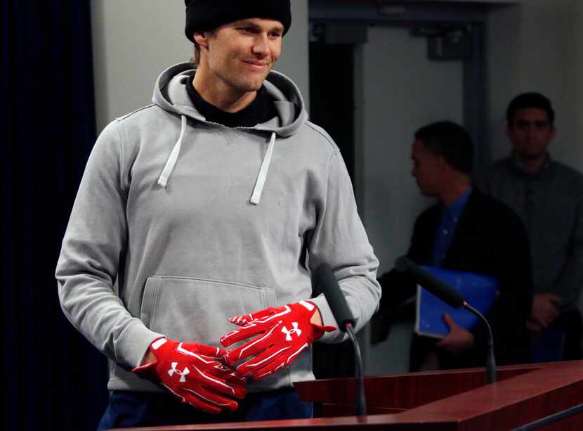 New England Patriots quarterback Tom Brady wears gloves as he arrives to speak to the media,...