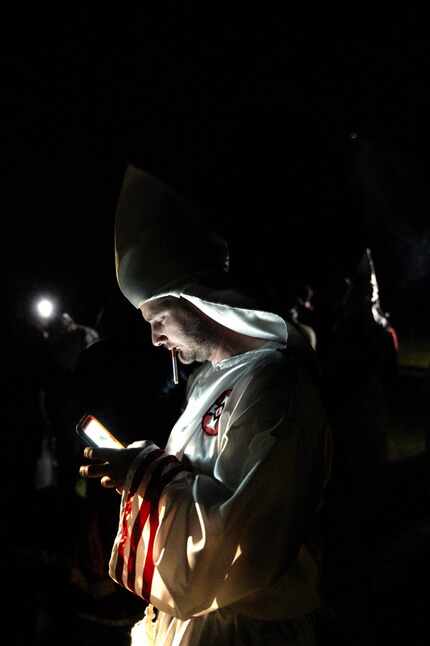 In this Saturday, April 23, 2016 photo, a member of the Ku Klux Klan uses a mobile device...