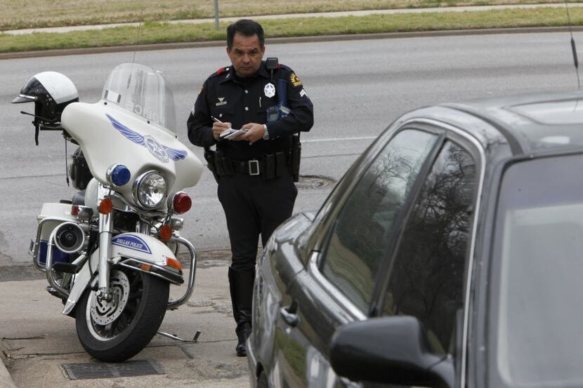 A Dallas police motorcycle officer writes a ticket in 2010. DPD officers have been writing...