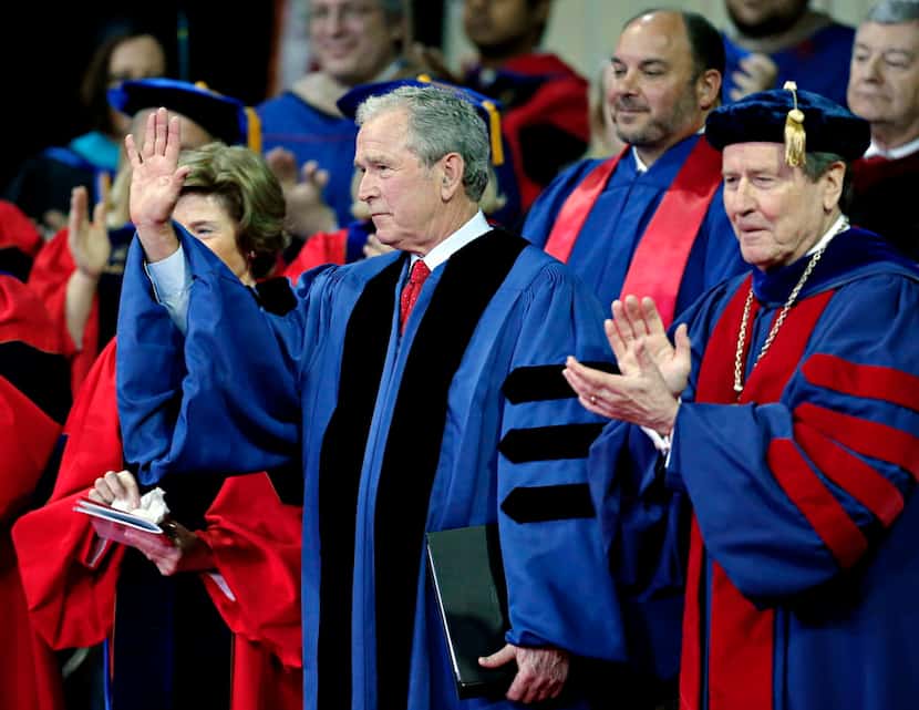 President George W. Bush (center) waves as he receives a applause following his address...