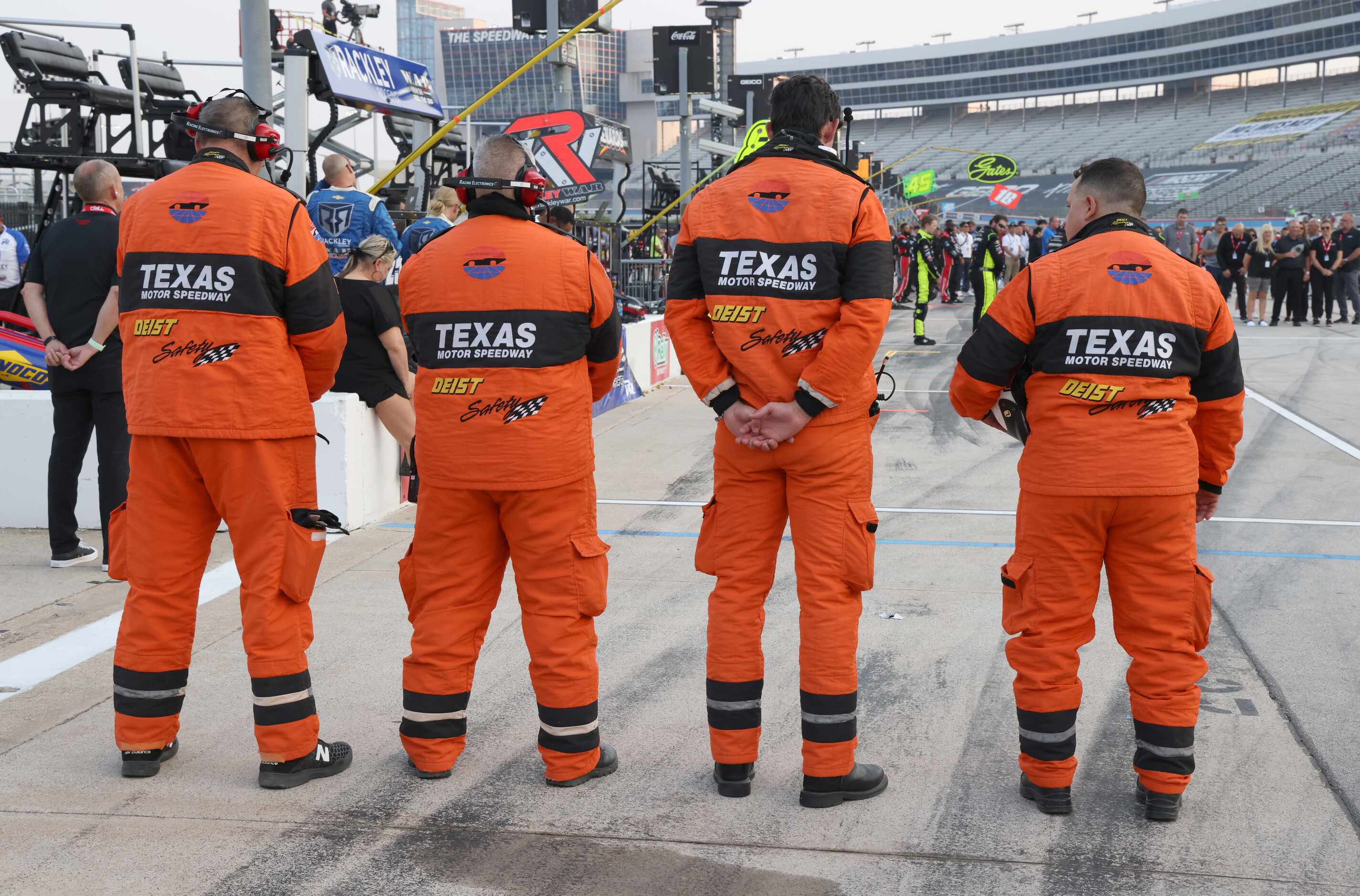 Members of a racing team pause on the track during a prayer before the start of the race....