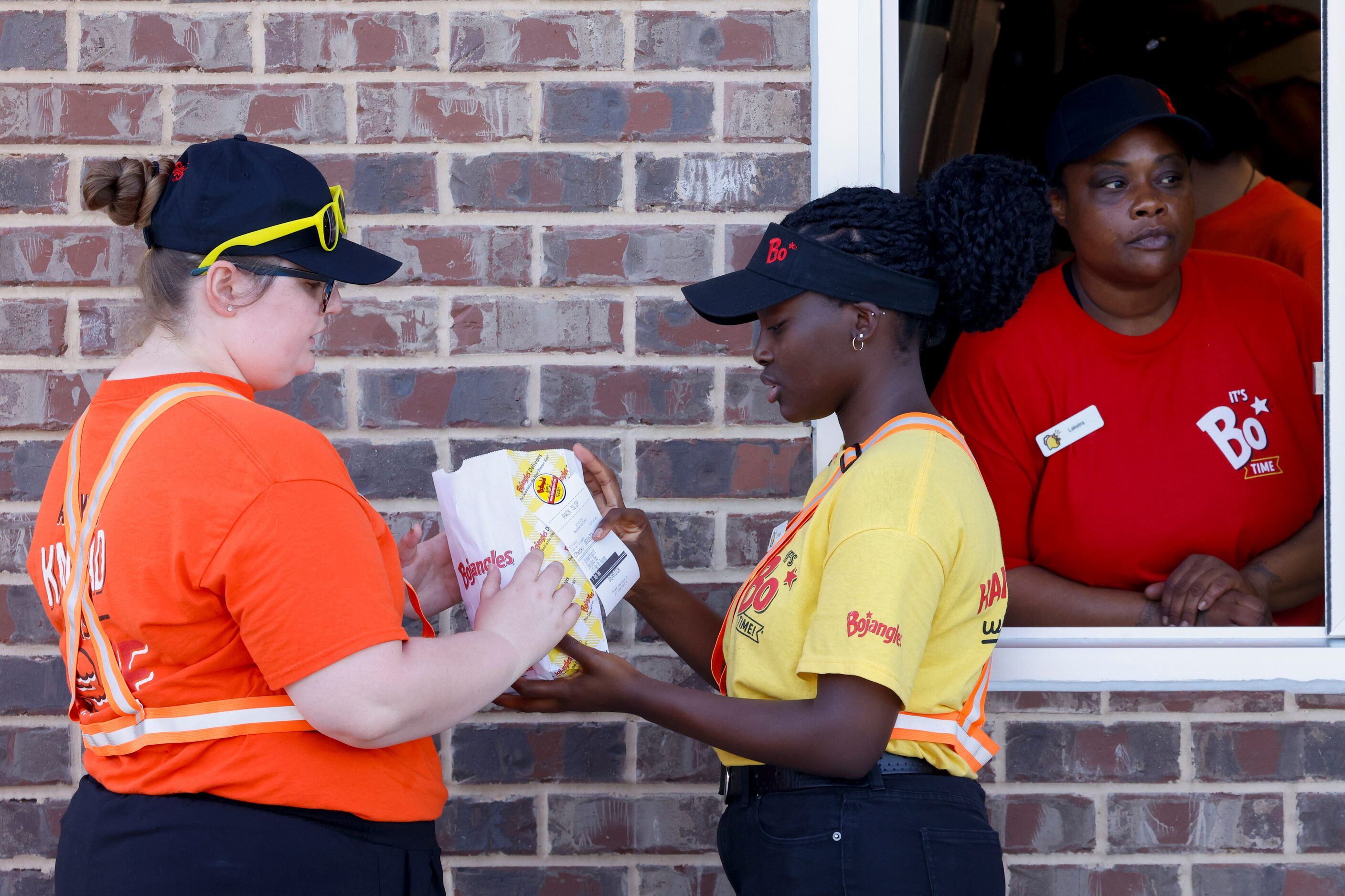 Employees Rachel Delashmutt (left) verifies a drive through order with Emike Anaani during...