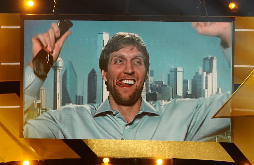 Basketball player Dirk Nowitzki is seen on a giant screen celebrating with the trophy of...