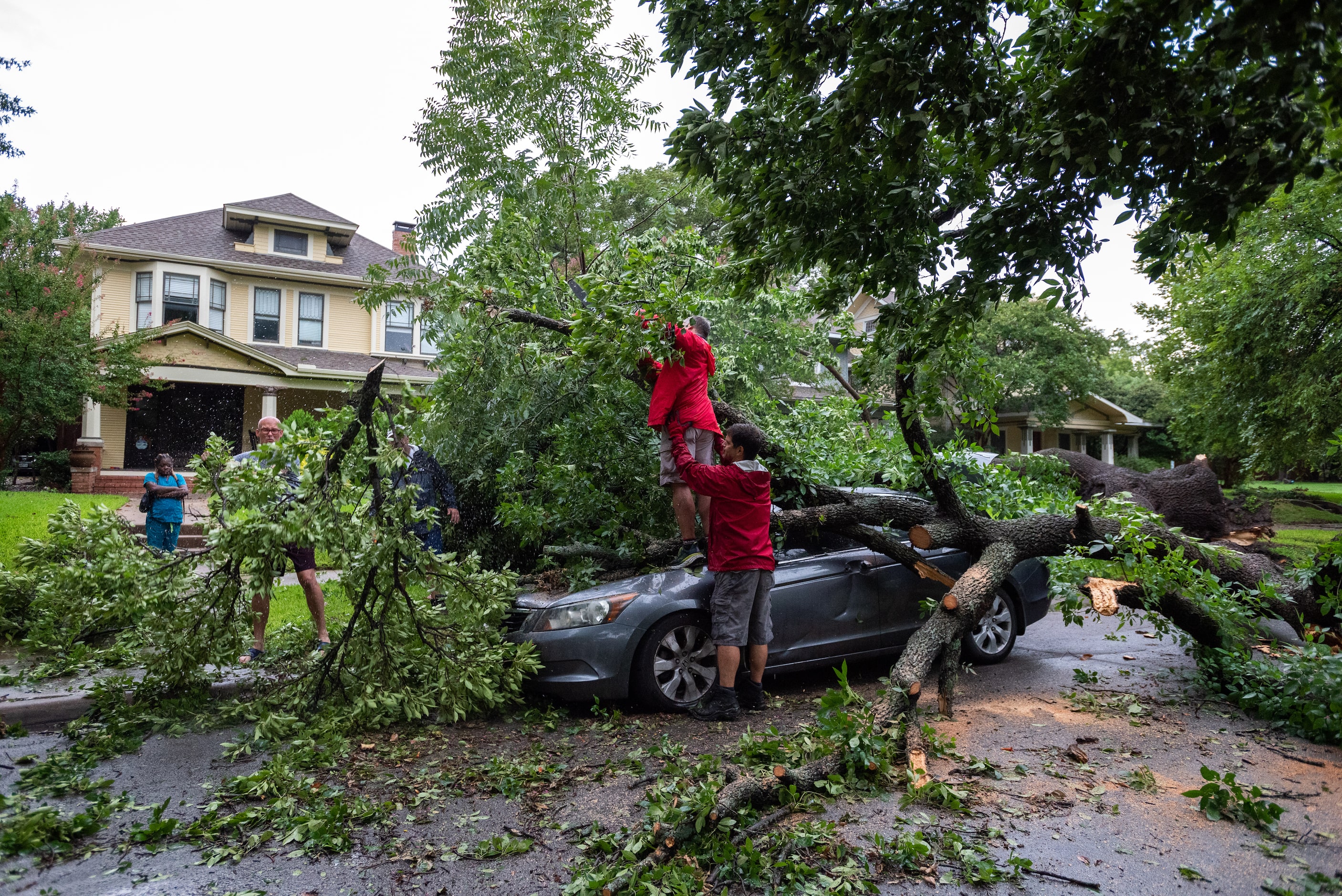 Mark Guest, 55, stands on a vehicle with the help of neighbor Eric Warheit, 51, as Guest...