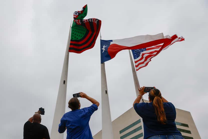 Attendees take photos of the newly raised Juneteenth flag  during an event in honor of the...