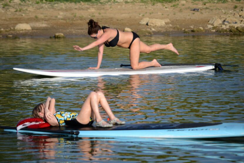 Holly Henry (top) of Lake Dallas completes a stretch during Paddleboard yoga on Lewisville...