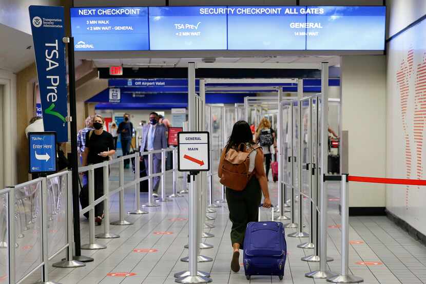 Travelers make their way to a security checkpoint at DFW International Airport's Terminal C...
