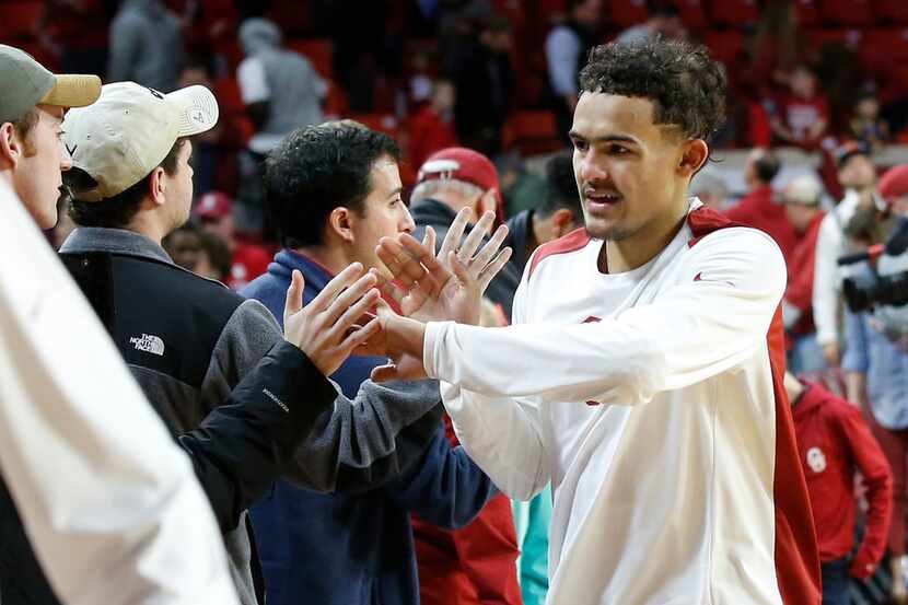 Oklahoma guard Trae Young slaps hands with fans following an NCAA college basketball game...