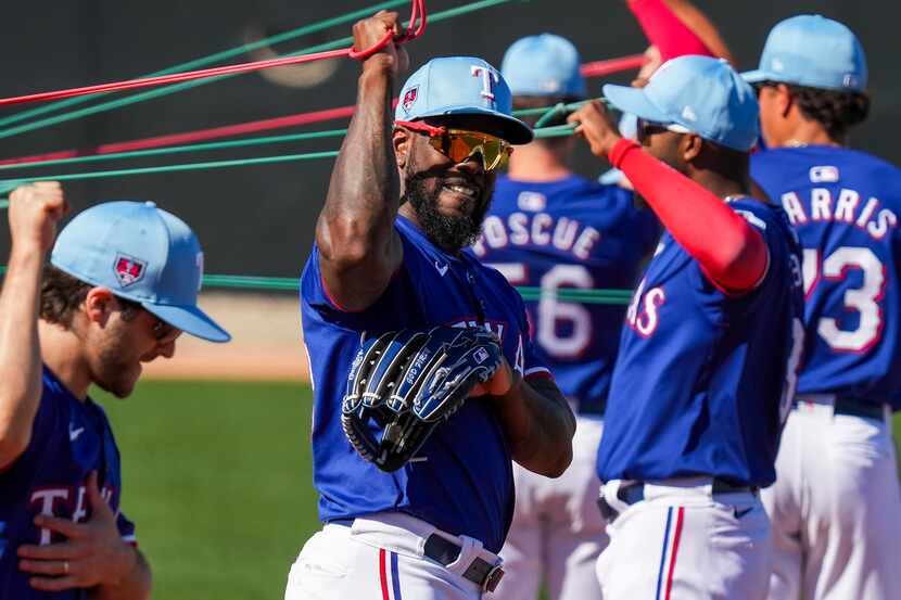 Texas Rangers outfielder Adolis García stretches with teammates during a spring training...
