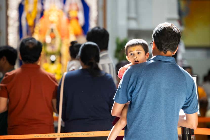 Ravichandran Balashanmugam holds daughter Vaira, 3, while visiting the altar of deities Sri...