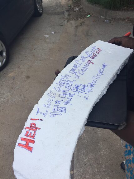 A woman at the Harwood Street homeless encampment writes a sign after she was told to move. 