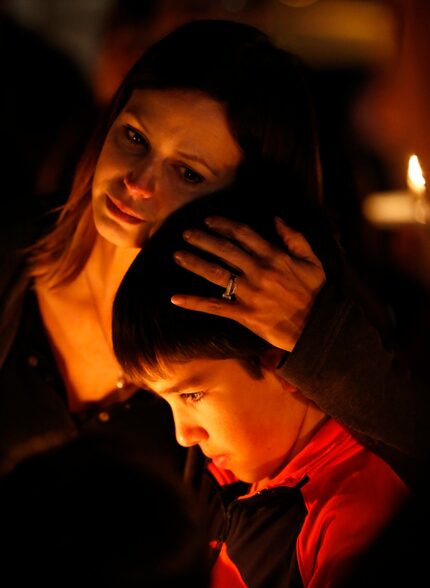  Cate Biggs (left), one of the organizers, hugs Benny Bonner, 9, during a prayer vigil...