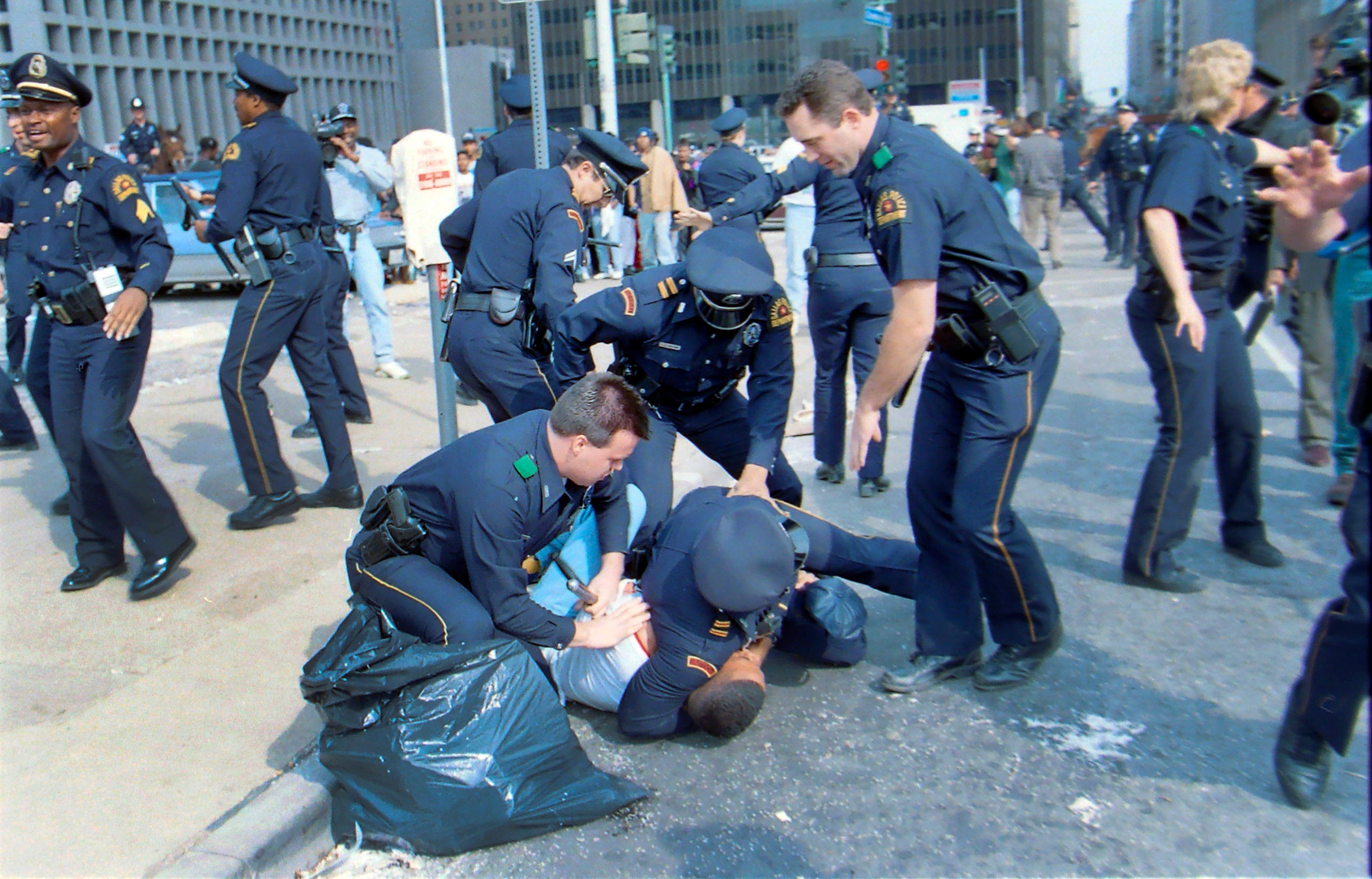 Dallas Police officers tackle a teenager after violence erupted along Commerce St following...