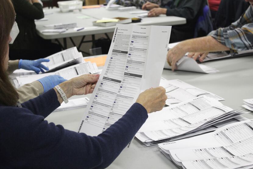 An election worker examines a ballot at the Clackamas County Elections office on May 19,...