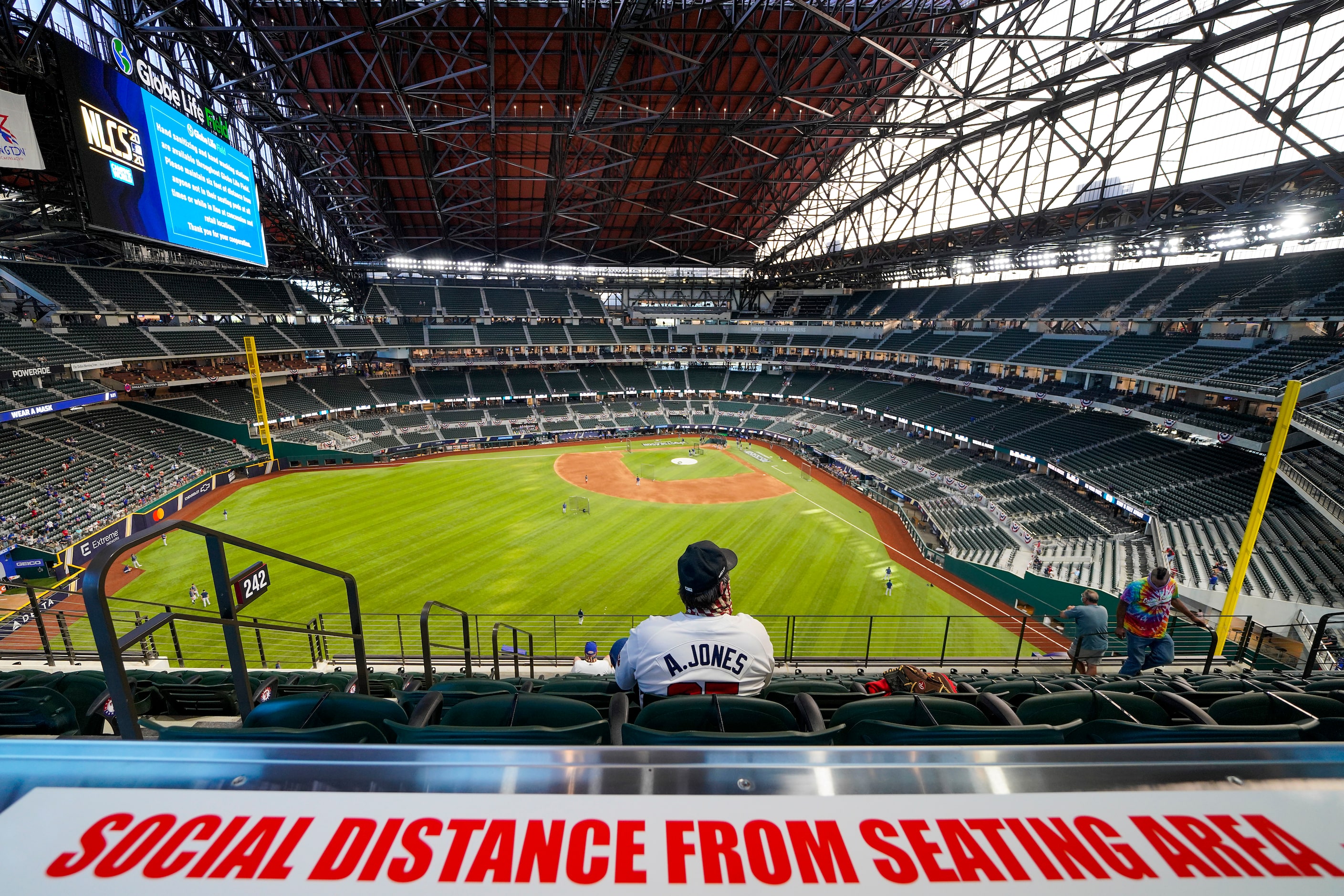 Signs encourage social distancing as a fan watches batting practice before Game 1 of a...