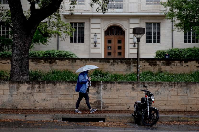 A woman passes by a stretch of open motorcycle parking spots on the University of Texas...