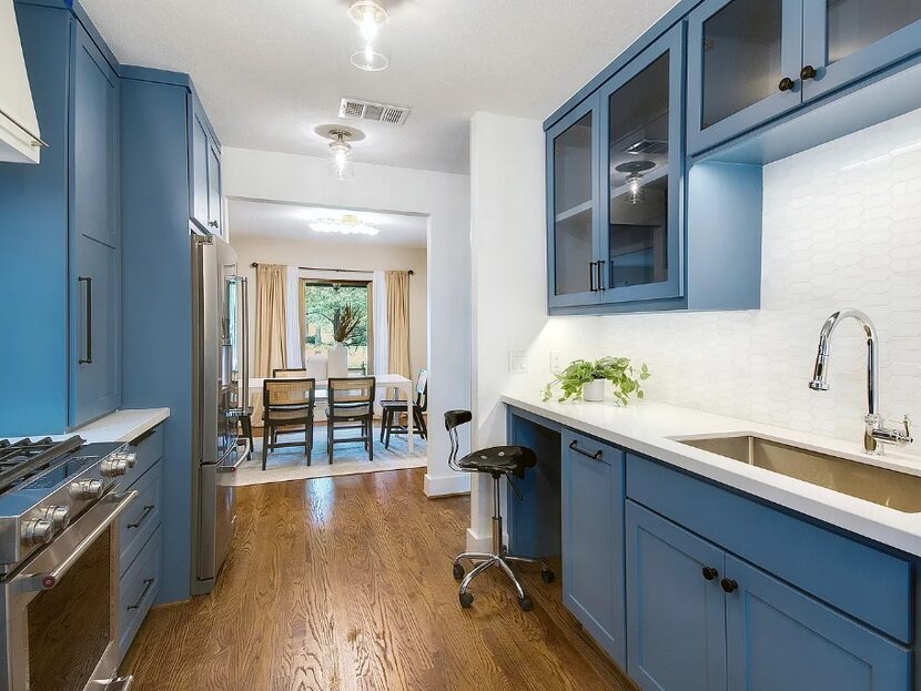 Blue kitchen with wood floors and a dining room in the distance