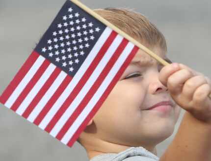 Alex Medina, 3, of Mansfield, waves an American flag at the 52nd annual 4th of July Parade...