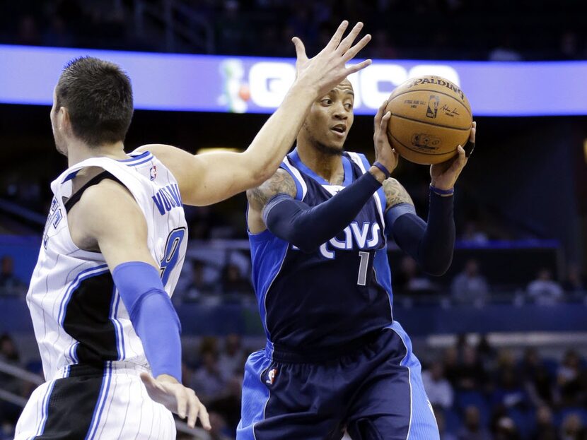 Dallas Mavericks' Monta Ellis, right, passes the ball around Orlando Magic's Nikola Vucevic,...