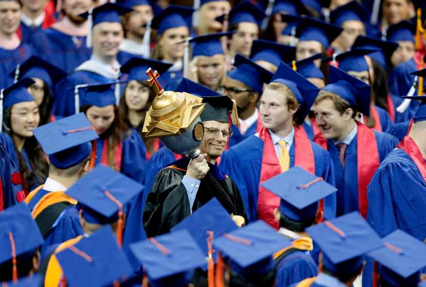 The official university mace is carried past graduating students during the SMU May...
